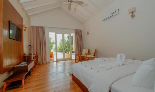 ein Schlafzimmer mit einem großen weißen Bett und einem TV in der Unterkunft Hondaafushi Island Resort in Vaikaradhoo