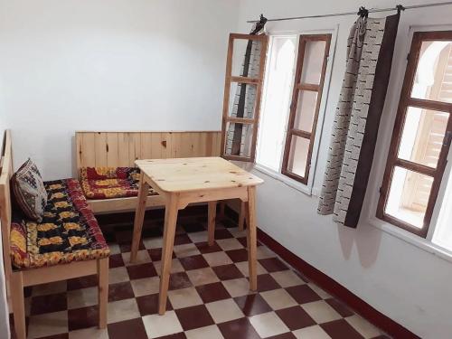 a room with a table and a bench and windows at Vallparadis Pension Familiar" FIRDAUS" in Chefchaouene