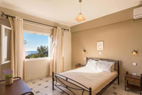 a bedroom with a bed and a large window at Large apartment by the pool - Pelekas Beach, Corfu in Pelekas