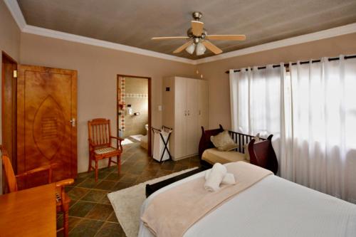 1 dormitorio con 1 cama y ventilador de techo en Amarachi Guesthouse, en Swakopmund
