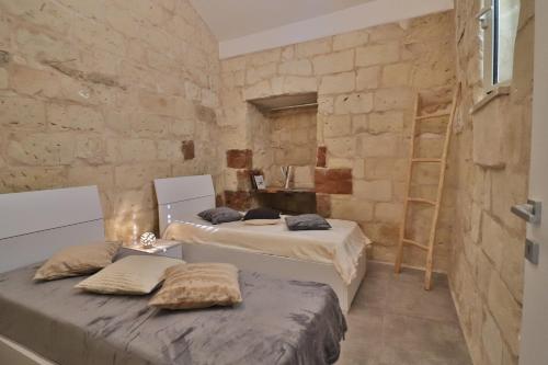 2 Betten in einem Zimmer mit einer Steinmauer in der Unterkunft Rebecca historic residence in Otranto in Otranto
