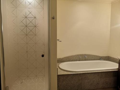 a bath tub in a bathroom with a shower backdoor at Apartment at Michelangelo Towers in Johannesburg