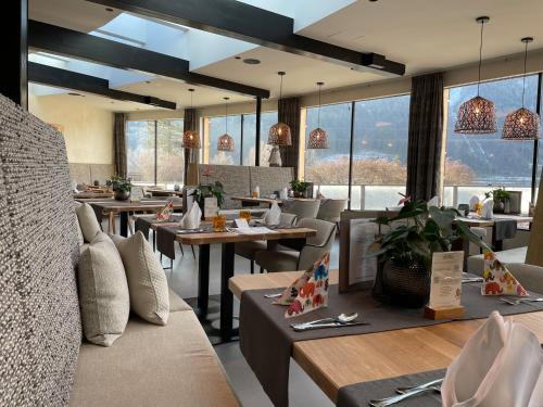 a restaurant with tables and chairs and large windows at Familienresort Buchau in Maurach