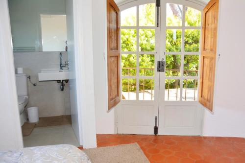 ein Bad mit einem Waschbecken und eine Tür mit einem Fenster in der Unterkunft Castellaras Le Vieux in Mouans-Sartoux