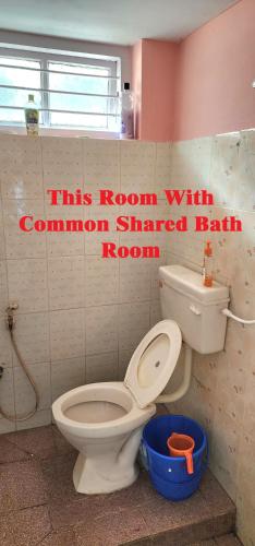 a bathroom with a toilet and a sign that reads this room with common shared bathroom at JJ's White House in Trichūr