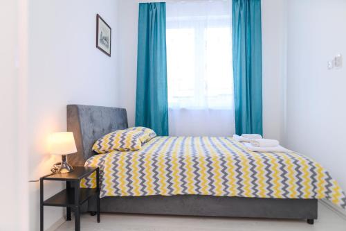 a bedroom with a bed with blue curtains and a window at Apartman MASTER in Soko Banja