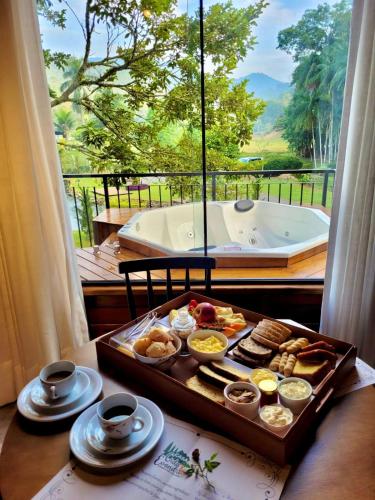 a tray of food on a table in front of a window at Pousada e Restaurante Casa Cida e Evandro in Gaspar