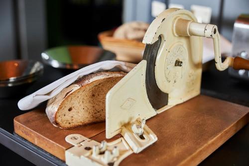 a loaf of bread on a cutting board next to a slicer at ERCK- Flair Hotel & Restaurant in Bad Schonborn