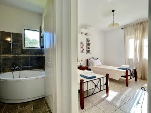 a bathroom with a bath tub and a bedroom at Villa Hephaestus Spartia Kefalonia in Spartià