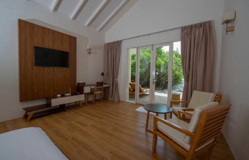 a living room with a bed and a tv and a table at Hondaafushi Island Resort in Vaikaradhoo