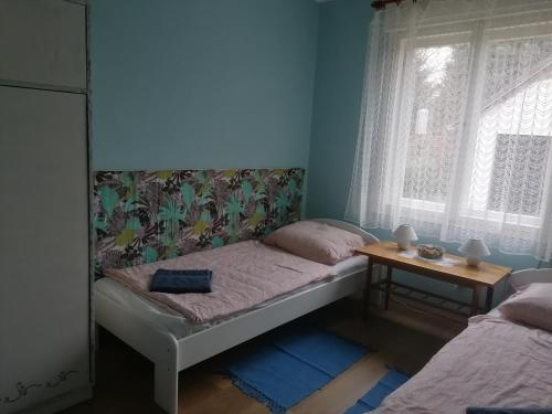 a small bedroom with a bed and a window at Zöld Liget Vendégház in Balatonfenyves