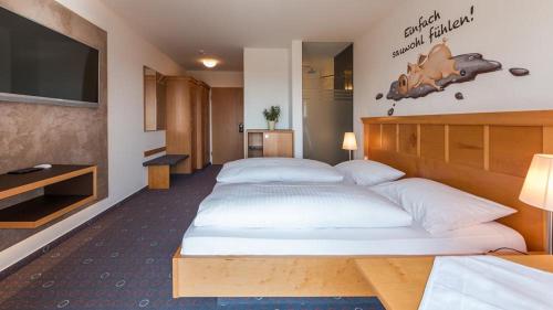 a hotel room with two beds and a flat screen tv at Landhaus Müller in Immenstaad am Bodensee