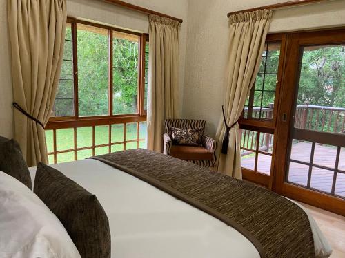 a bedroom with a bed and windows and a chair at Kruger Park Lodge, Kubu Lodge 224 in Hazyview