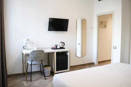 a bedroom with a desk with a television and a bed at Hotel Donatello in Modena