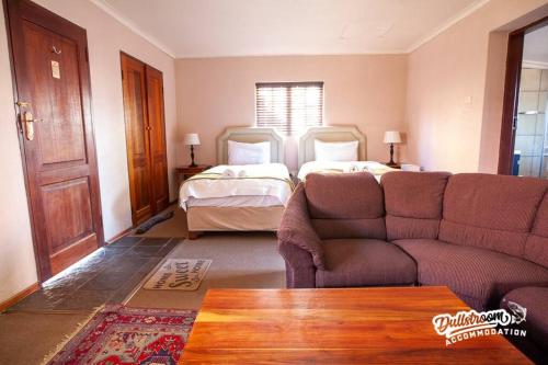 a living room with a couch and a bed at Duckling Cottage in Dullstroom