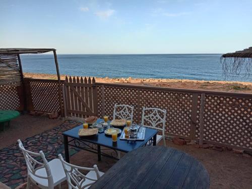 a table and chairs on a balcony with the beach at Dar diafa samira in Mirleft