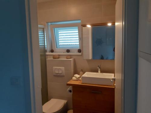 La salle de bains est pourvue d'un lavabo, de toilettes et d'une fenêtre. dans l'établissement Apartment Nikica (with sea view, garden, parking), à Selce