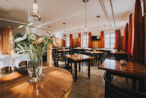 een restaurant met houten tafels en stoelen en een vaas met bloemen bij Hotel Landgasthof Zur Post in Mengkofen