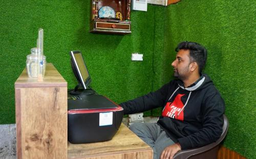 a man sitting at a table with a laptop computer at Secret Staycation Nature Cottages in Kandāghāt