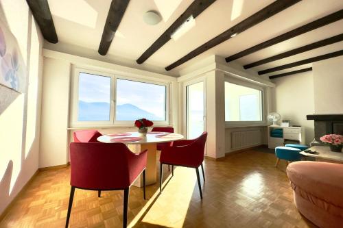 ein Wohnzimmer mit einem Tisch, Stühlen und Fenstern in der Unterkunft Bellevue Apartment - Happy Rentals in Ronco sopra Ascona