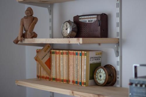 un estante de libros con libros y relojes. en a casa da Alicia, en Monforte de Lemos