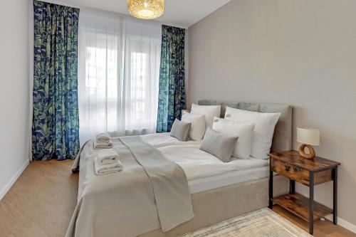 ein weißes Bett in einem Zimmer mit Fenster in der Unterkunft Downtown Apartments Śląska 12 in Danzig