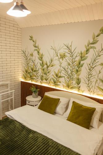 a bedroom with a large bed with green plants on the wall at Комплекс На Дачі in Vyshpolʼ