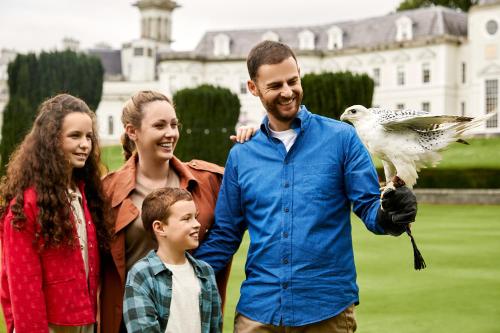 a man and a family holding a bird in front of a house at The K Club in Straffan
