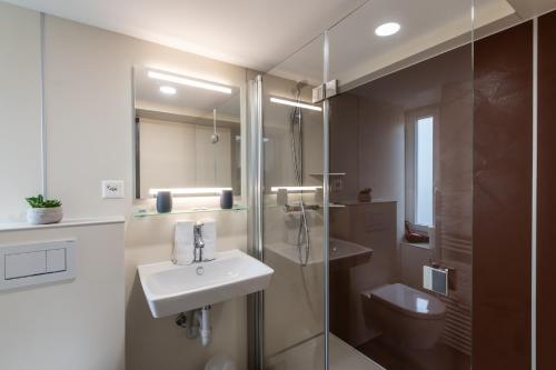 a bathroom with a sink and a shower and a toilet at Hotel Greina in Rabius