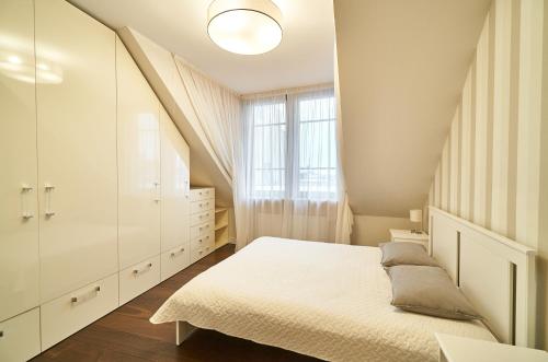 een witte slaapkamer met een bed en een raam bij EMI Apartment in Rīga