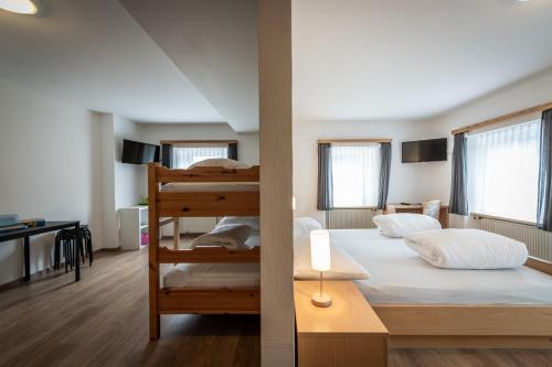 a bedroom with two bunk beds and a desk at Hotel Greina in Rabius