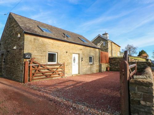 a stone barn with a wooden gate and a fence at Stable Cottage in Brampton