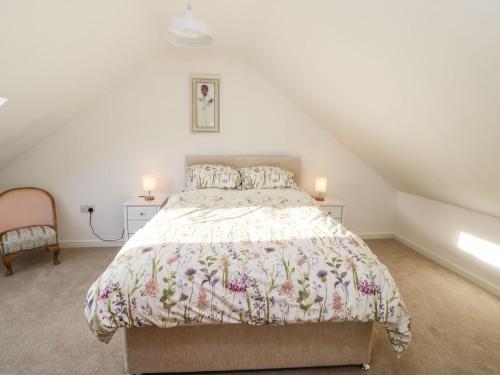 a bedroom with a bed with a floral bedspread at Stable Cottage in Brampton