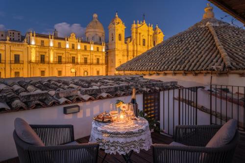una mesa y sillas en un balcón con un edificio en San Carlo Suites, en Noto