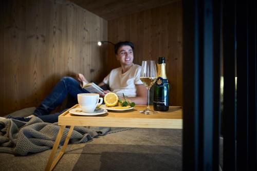 Aparthotel Chalina في لوتاش: رجل يجلس على طاولة مع كوب من النبيذ
