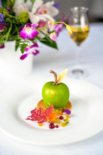 a green apple on a plate next to a vase of flowers at The K Club in Straffan