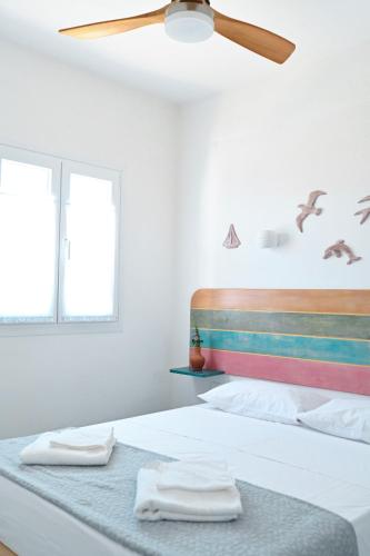 a white bedroom with a bed with a ceiling fan at Dolce Vista - Sea View Apartments in Parikia