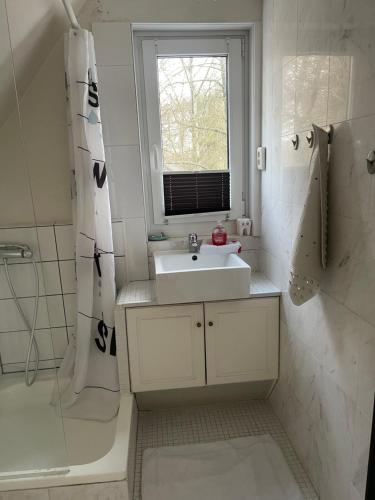 een witte badkamer met een wastafel en een raam bij Ruhige Doppelhaushälfte mit 5 Schlafzimmern im Villenviertel in Hamburg