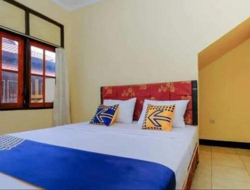 a bedroom with a bed with blue and white pillows at The Ellen Hotel by ecommerceloka in Senggigi