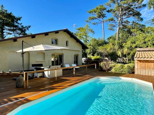 une maison avec une piscine sur une terrasse en bois dans l'établissement Ferienhaus mit beheiztem Pool in Claouey, à Lège-Cap-Ferret
