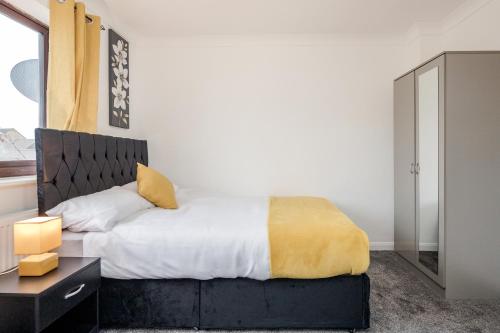 a bedroom with a bed with a yellow blanket at Lovely House in Dagenham / Barking with free parking, WiFi & Garden in Dagenham