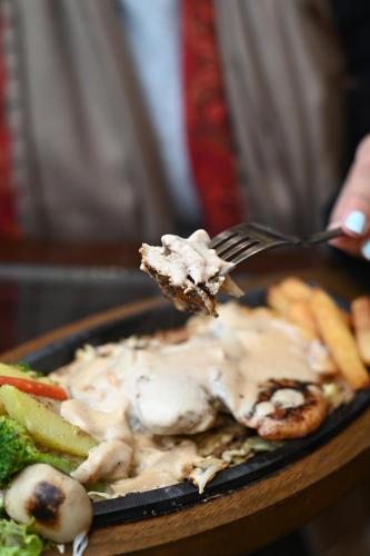 a person eating a plate of food with a fork at Royal Regency Hotel in Islamabad