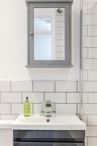 a white bathroom with a sink and a mirror at Lovely House in Dagenham / Barking with free parking, WiFi & Garden in Dagenham