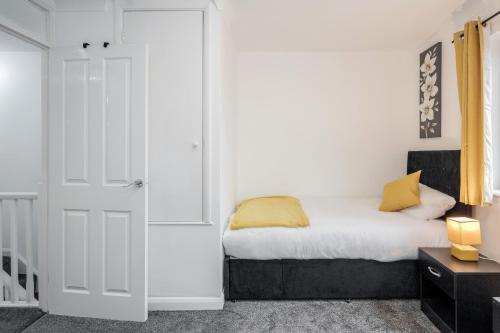 a bedroom with a bed with yellow pillows on it at Lovely House in Dagenham / Barking with free parking, WiFi & Garden in Dagenham