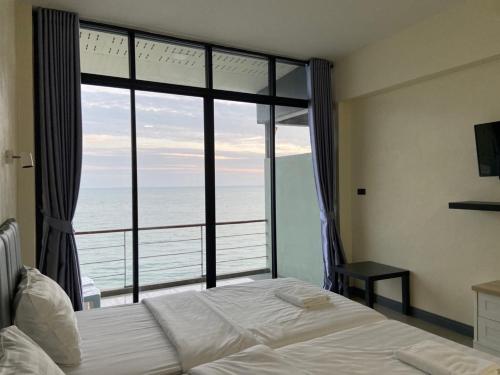 een slaapkamer met een bed en uitzicht op de oceaan bij Phala Shore Resort 