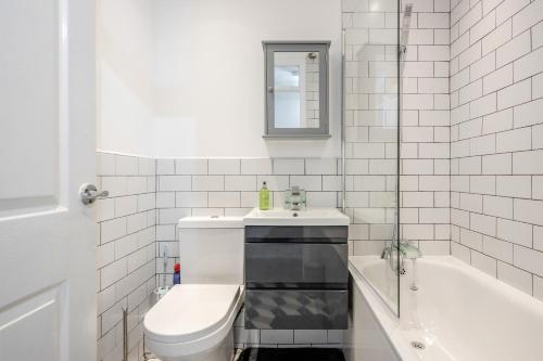 a bathroom with a sink and a toilet and a tub at Lovely House in Dagenham / Barking with free parking, WiFi & Garden in Dagenham