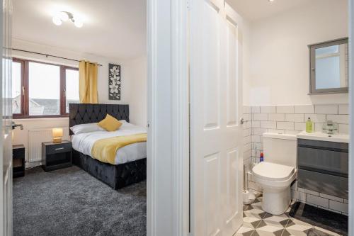 達格納姆的住宿－Lovely House in Dagenham / Barking with free parking, WiFi & Garden，一间卧室设有一张床、一个卫生间和一个水槽