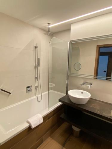 a bathroom with a sink and a glass shower at Hotel Aaritz in Selva di Val Gardena