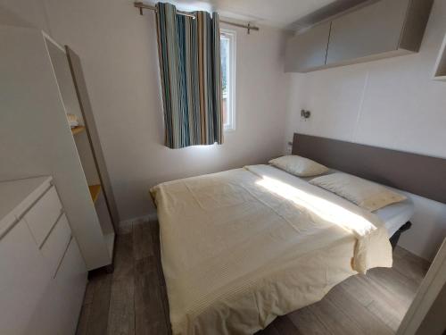 a small bedroom with a bed and a window at Mobile home Happy days in Sveti Juraj