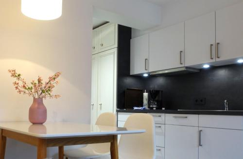 a kitchen with white cabinets and a table with a vase of flowers at Inselresidenz Strandburg Juist - Ferienwohnung 308 (Ref. 51039) in Juist